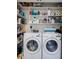 Functional laundry room featuring a side-by-side washer and dryer, with shelving stocked full of cleaning supplies at 705 Berry Ct, Villa Rica, GA 30180