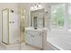 Bright bathroom featuring a glass shower, soaking tub, and white vanity with a large window at 1130 S Rudder Rd, Cumming, GA 30041