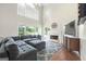 A living room with a cozy fireplace, tall ceilings, a ceiling fan, and a grey L-shaped couch at 1130 S Rudder Rd, Cumming, GA 30041