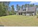 Expansive green lawn surrounds the home with a backdrop of tall trees, ensuring privacy at 120 Laurel Forest Dr, Tyrone, GA 30290