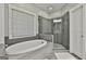 Modern bathroom features a soaking tub, glass enclosed shower with gray tile surround and decorative window at 120 Laurel Forest Dr, Tyrone, GA 30290