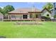 Large backyard with deck, lush green lawn, flower bed, screened in porch, and mature trees at 411 Baneberry Bnd, Peachtree City, GA 30269