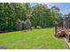 Backyard features a spacious lawn, wooded perimeter, garden, and deck stairs at 411 Baneberry Bnd, Peachtree City, GA 30269