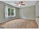 Neutral bedroom featuring carpeted floors, a ceiling fan, and a large window at 411 Baneberry Bnd, Peachtree City, GA 30269