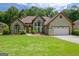 Charming exterior featuring a well-manicured lawn, lovely landscaping, and an attached two-car garage at 411 Baneberry Bnd, Peachtree City, GA 30269