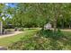 Expansive backyard featuring a lush lawn, mature trees, a storage shed, and a charming stone patio with outdoor seating at 115 Roscommon Ct, Tyrone, GA 30290