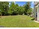 Large, green backyard featuring a storage shed and bordering trees at 115 Roscommon Ct, Tyrone, GA 30290