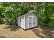 Well-maintained outdoor shed with double doors and a window, providing ample storage space in a wooded backyard setting at 115 Roscommon Ct, Tyrone, GA 30290