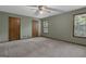 Spacious bedroom with neutral carpet, two windows, and multiple closet doors at 886 Pine Needle Rd, Hampton, GA 30228