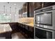 Gourmet kitchen featuring stainless steel double ovens, gas cooktop, granite countertops, and dark wood cabinetry at 162 Aylesbury Blvd, Mcdonough, GA 30252