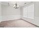 An empty living room featuring crown molding, neutral carpet, and a chandelier at 162 Aylesbury Blvd, Mcdonough, GA 30252