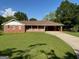 Traditional brick home with a well-manicured lawn and a long driveway under a blue sky at 18 North Ave, Hampton, GA 30228
