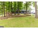 View of the two-story house with dark siding from the front yard, showing the trees and landscaping at 870 The Cir, Lawrenceville, GA 30043