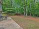 A spacious backyard features an outdoor seating area and plenty of open space surrounded by lush, mature trees at 445 Royal St, Mcdonough, GA 30253