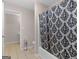 Bathroom featuring tan tile floors, a toilet, and a black and white patterned shower curtain at 445 Royal St, Mcdonough, GA 30253