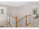 Upstairs hallway with carpeted floors and staircase with oak railing and white balusters at 445 Royal St, Mcdonough, GA 30253