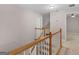 Hallway with carpeted floors, staircase with oak railing and white balusters at 445 Royal St, Mcdonough, GA 30253