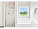 Relaxing primary bath with a separate shower, tub, and a window offering backyard views at 715 Colvin Dr, Locust Grove, GA 30248