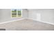 Well-lit bonus room featuring neutral carpet, a window offering natural light, and a door at 715 Colvin Dr, Locust Grove, GA 30248