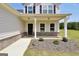 Close-up of a charming front porch with brick accents, a welcoming door, and landscaped garden beds at 715 Colvin Dr, Locust Grove, GA 30248