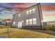The rear view of a home at dusk, highlighted by large windows, light siding, brick accents, and a grassy yard at 3460 Sycamore Sw Dr, South Fulton, GA 30331