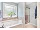 Bathtub with jets, stone backsplash, sliding glass shower door, and light blue walls at 1211 Fly Rod Ln, Loganville, GA 30052