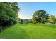 Expansive backyard with a lush green lawn, mature trees, and a charming brick home in the distance at 161 Pleasant Grove Rd, Mcdonough, GA 30252