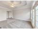 Bright main bedroom features neutral carpet, tray ceiling, and multiple windows with backyard views and natural light at 161 Pleasant Grove Rd, Mcdonough, GA 30252