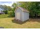Backyard view showcasing a storage shed with double doors set on a well-kept lawn, surrounded by a black fence at 207 Brookstone Dr, Carrollton, GA 30116