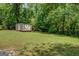 View of backyard with shed and a lawn area surrounded by trees at 357 Oak Hill Rd, Covington, GA 30016