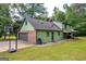 Side view of a two-story home with a basketball hoop, covered porch, and green siding at 74 Price W Dr, Locust Grove, GA 30248
