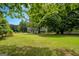 View of backyard with the main home and shed as seen through the trees at 74 Price W Dr, Locust Grove, GA 30248