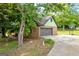 View of the brick two-car garage with a concrete driveway and mature trees at 74 Price W Dr, Locust Grove, GA 30248