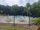 Community pool featuring lounge chairs and umbrellas, enclosed by a black metal fence for safety and privacy at 312 Archway Ln, Peachtree City, GA 30269