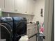 Well-equipped laundry room with front-load washer and dryer, built-in cabinets, and utility sink at 312 Archway Ln, Peachtree City, GA 30269