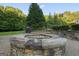 Outdoor fire pit with stone surround and a view of the lush landscaped backyard at 885 Kelleytown Rd, Mcdonough, GA 30252