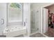 Bright bathroom features a soaking tub beneath a window, and a glass-enclosed shower at 1010 Capella Creek Way, Grayson, GA 30017