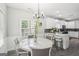 Bright dining area features a modern chandelier, windows, and flows into a white kitchen with gray accents at 1010 Capella Creek Way, Grayson, GA 30017