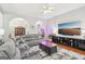An open-concept living room with hardwood floors, a plush gray sectional, and a large screen television at 1010 Capella Creek Way, Grayson, GA 30017
