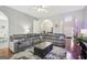 Spacious living room featuring hardwood floors, a plush gray sectional, and an elegant coffee table at 1010 Capella Creek Way, Grayson, GA 30017