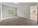 Carpeted bedroom featuring a window overlooking a greenery view and a doorway to the kitchen at 1429 Kentmire Court, Locust Grove, GA 30248