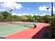 Well-maintained tennis court with green and red surfaces, surrounded by lush trees at 1429 Kentmire Court, Locust Grove, GA 30248