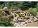 Picturesque rock waterfall cascading through lush greenery, enhancing the landscape's tranquility and beauty at 1429 Kentmire Court, Locust Grove, GA 30248
