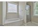 Bright bathroom features a garden tub and separate glass-enclosed shower, complemented by large windows at 100 Concord Ct, Fayetteville, GA 30214