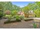 This backyard showcases a charming brick house with garden beds and a three-car garage at 9274 Betony Wood Trl, Jonesboro, GA 30236