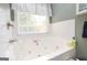 Close-up of a jetted tub with white tile surround and a window bringing in natural light at 208 Summer Chase, Carrollton, GA 30116