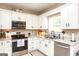 Well-appointed kitchen featuring stainless steel appliances, white cabinets, granite countertops and modern fixtures at 208 Summer Chase, Carrollton, GA 30116