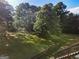 Large backyard with mature trees, a retaining wall, and stairs leading to the back of the house, perfect for outdoor activities at 1875 Bernice Dr, Cumming, GA 30041