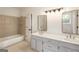 Bright bathroom featuring a double sink vanity, tub and neutral tile surround at 1875 Bernice Dr, Cumming, GA 30041