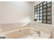 Bright bathroom features a jacuzzi tub with glass block window and tile surround at 1875 Bernice Dr, Cumming, GA 30041